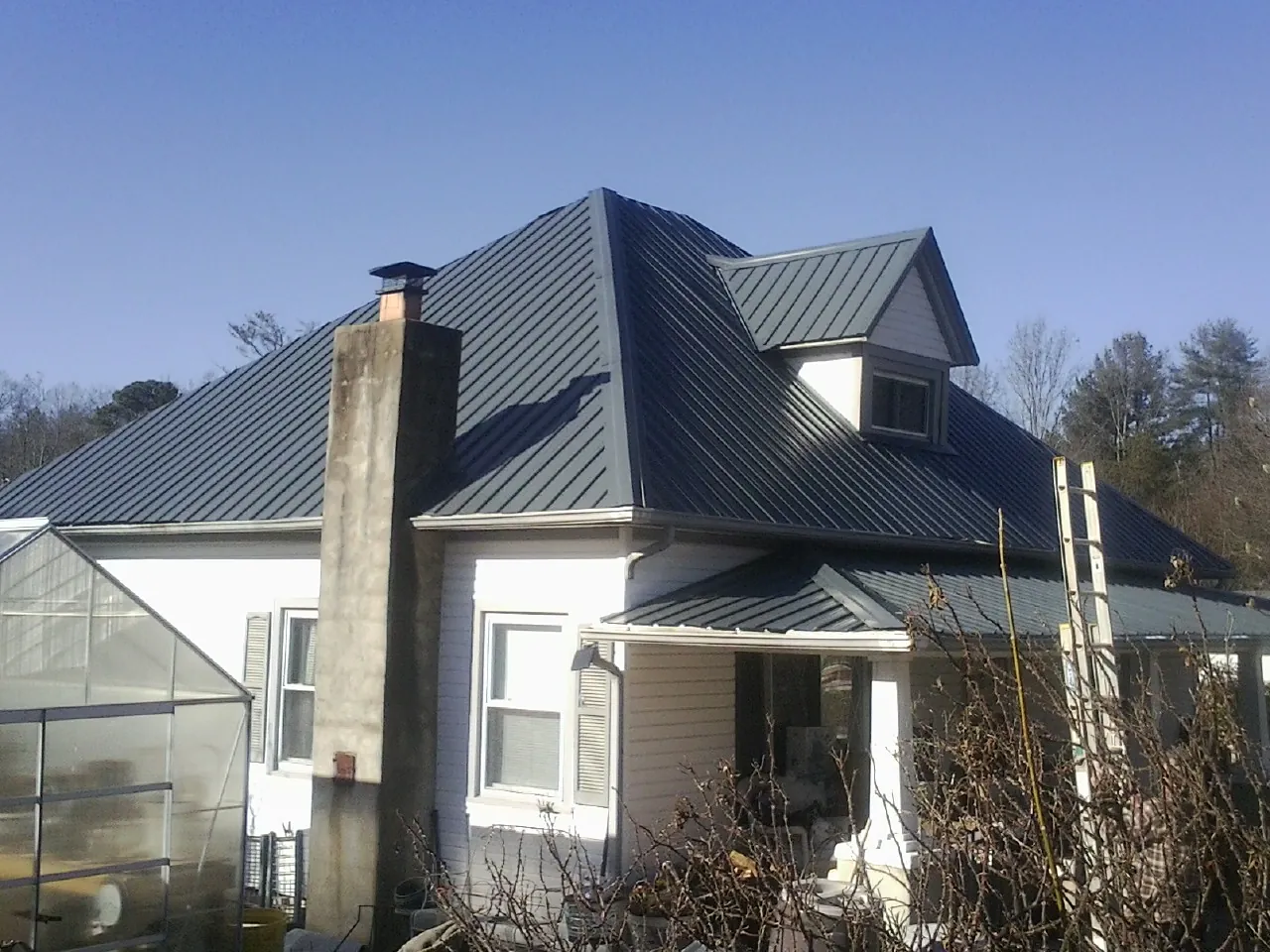 Dark blue standing seam metal roof on a white farmhouse with dormer — Slate & Tile Roof Repair by Roofing Brothers in Dysart