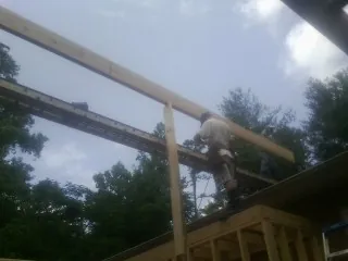 Carpenter setting a ridge beam over a new addition frame — Ice Dam Removal by Roofing Brothers in Dysart
