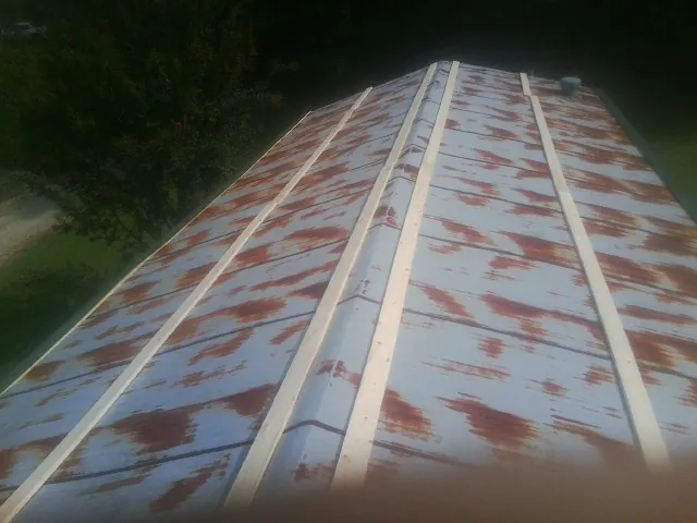 Rusted metal roof panels with new wood purlins before replacement — Storm Damage Roof Repair in Dysart by Roofing Brothers