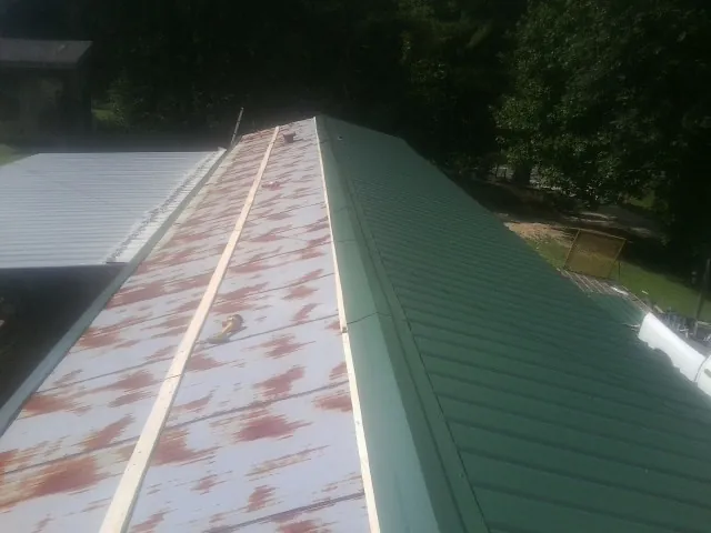 Old rusted panels beside newly installed green metal roofing — Wind Damage Roof Repair by Roofing Brothers in Dysart