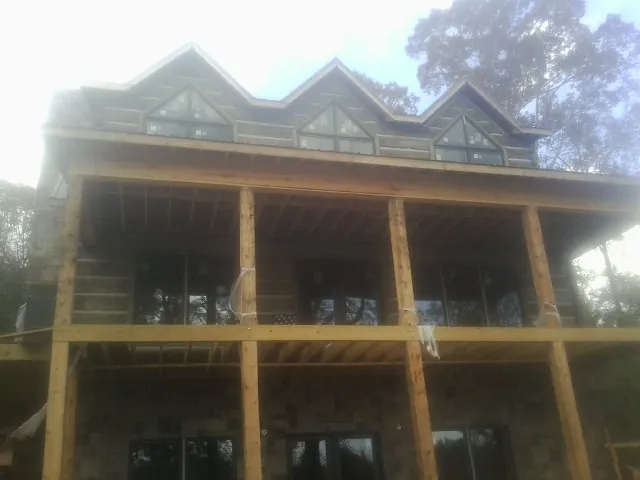 Dormers and porch framing on a large log home under construction — Roof Coating work by our crew in Dysart