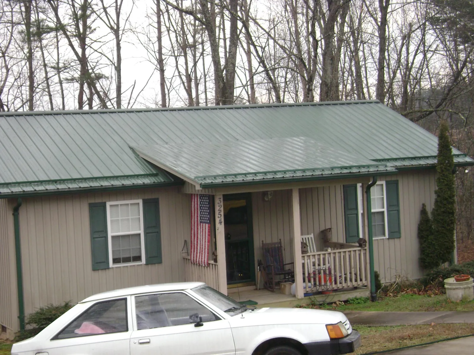 Green metal roof and front porch on a tan sided cottage in Dysart
