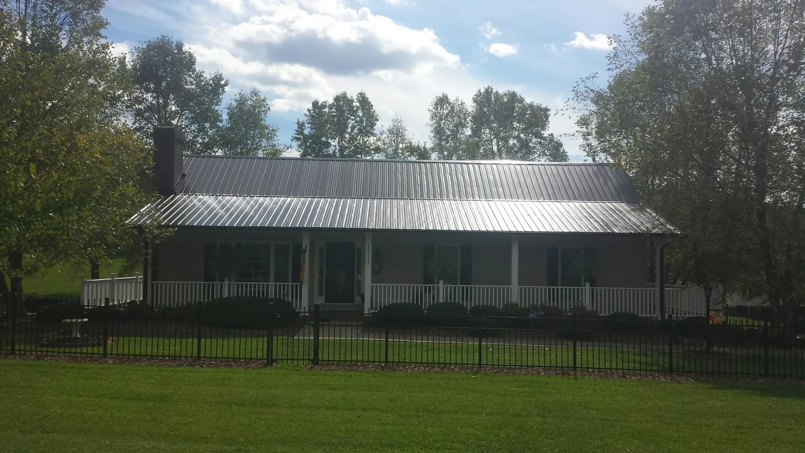 Gray metal roof on a brick ranch with a full width front porch — Gutter Guard Installation work by our crew in Dysart