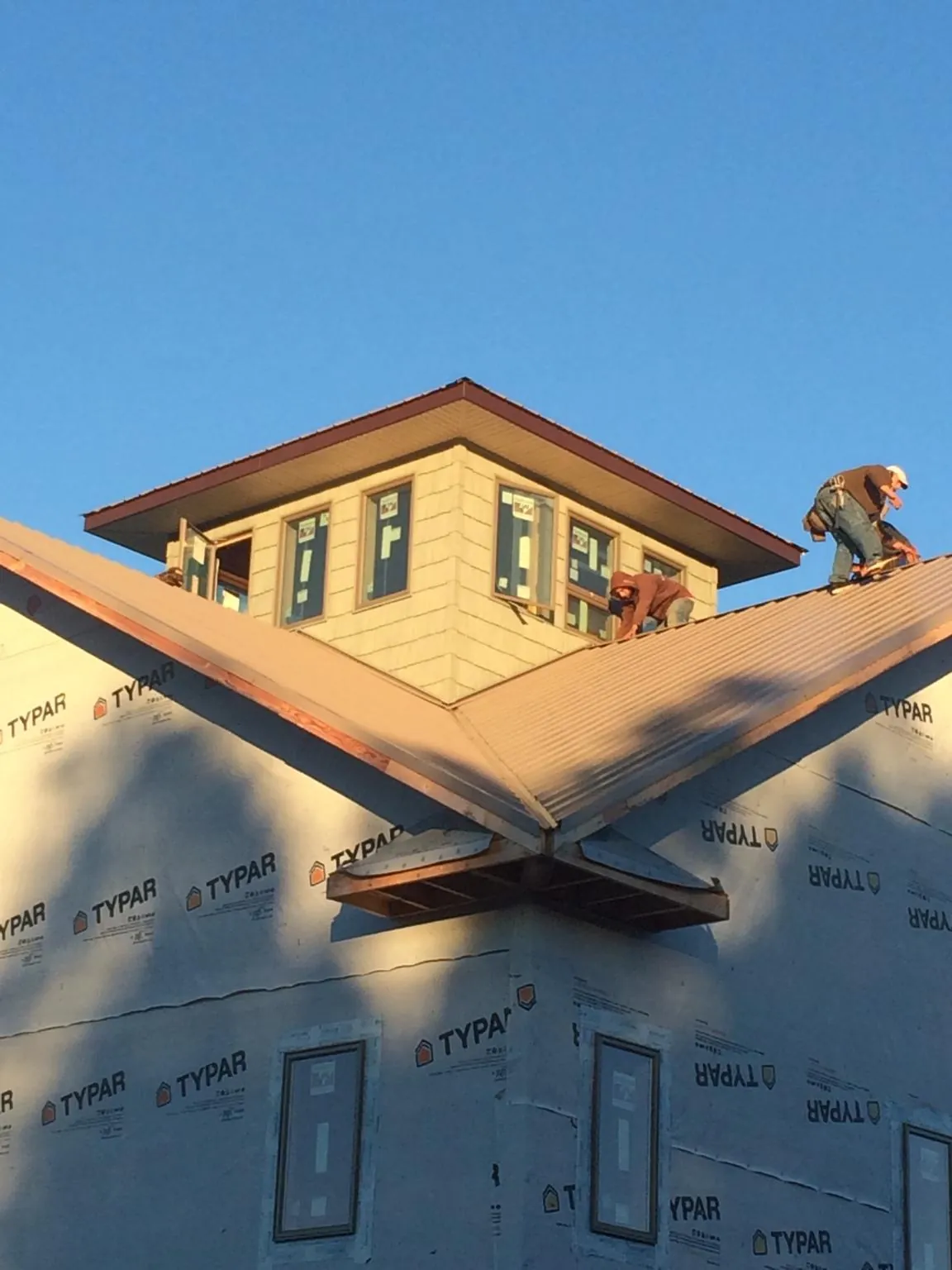 Roofers working around a rooftop cupola on a new metal roof at sunset — Roof Waterproofing in Dysart by Roofing Brothers